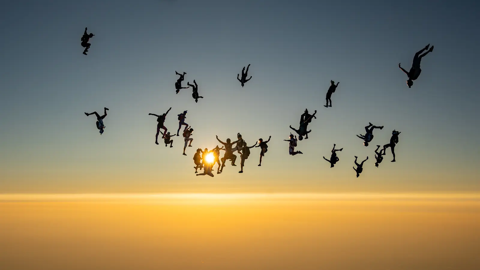 Formation de parachutistes en silhouette au coucher du soleil